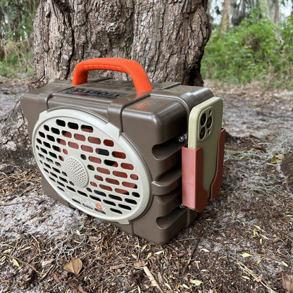 A brown Turtlebox Phone holder from Ruckus Marine holding an iPhone in the woods.